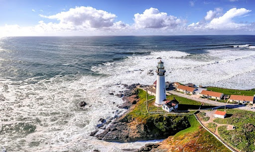 A lighthouse on a rocky headland above the California coast.